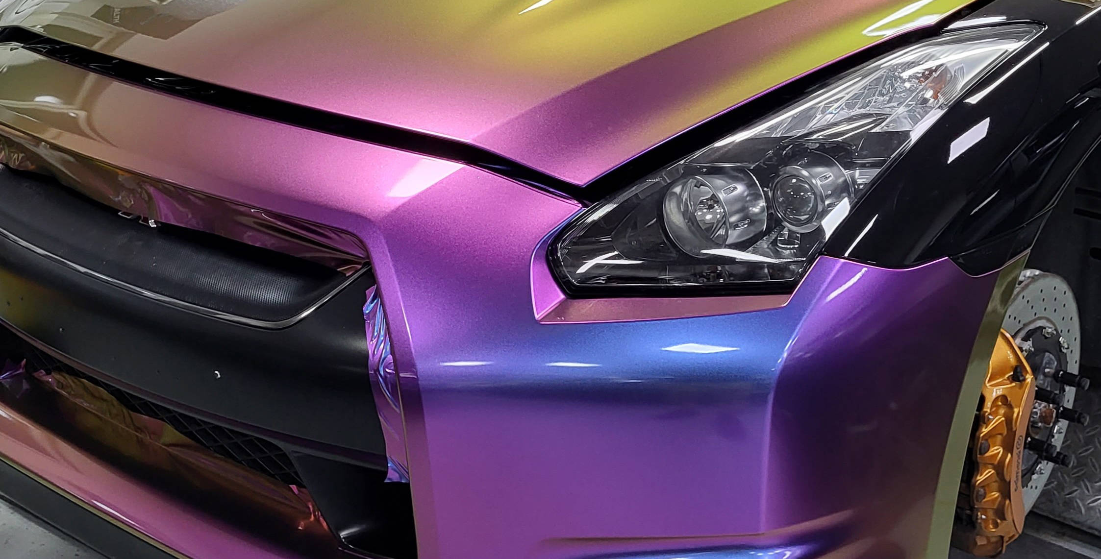 Detailiertes Car Wrapping in Garbsen bei AZ Folie. Hier ist eine bunte Folie zu sehen die gerade angebracht wird und noch nicht vollständig zugeschnitten ist